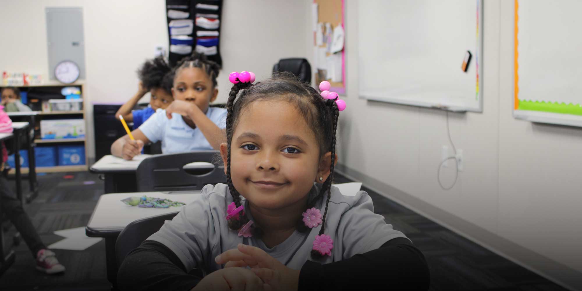 Smiling young student sitting at a classroom desk.